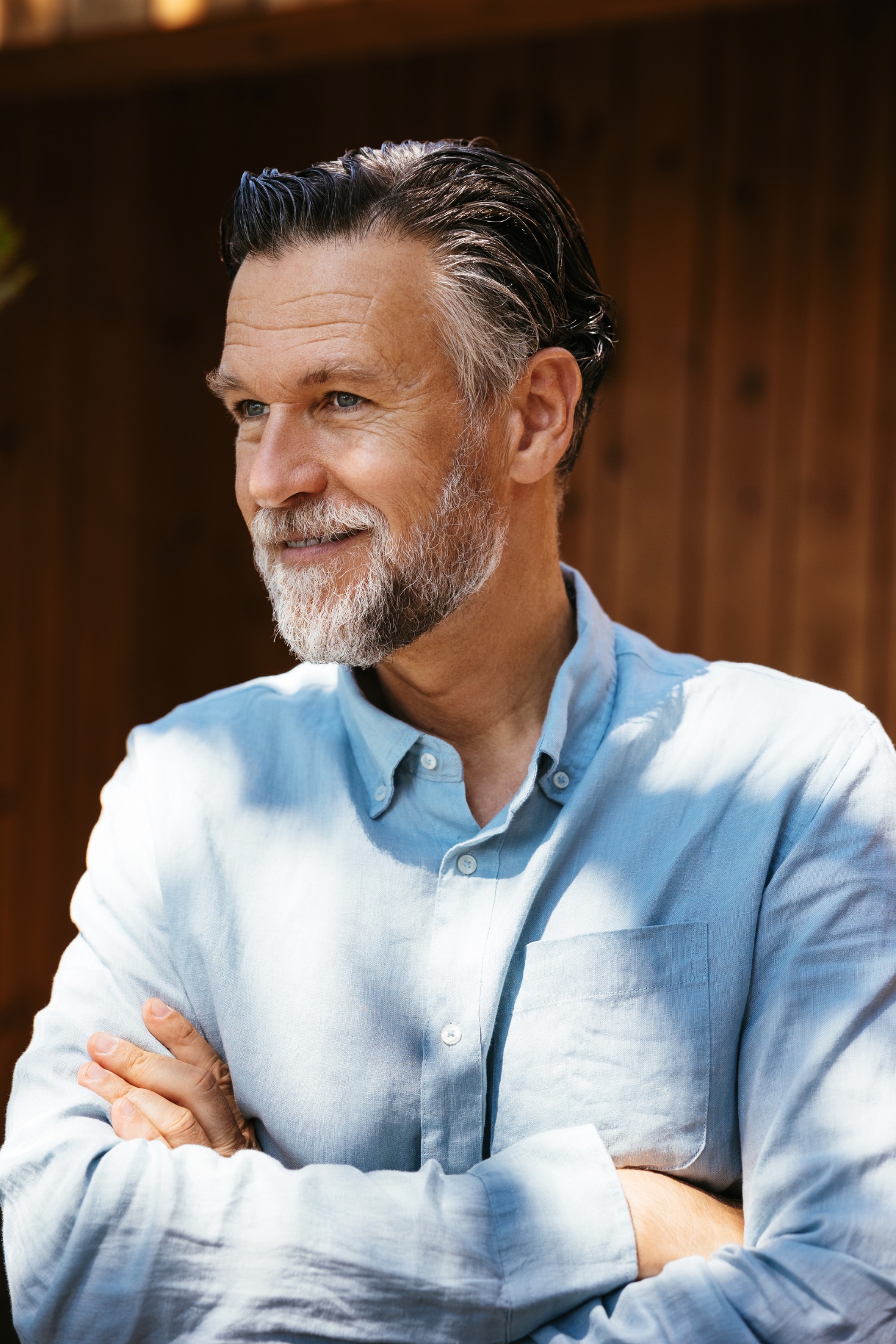 Composed, confident mature man with folded arms, natural light